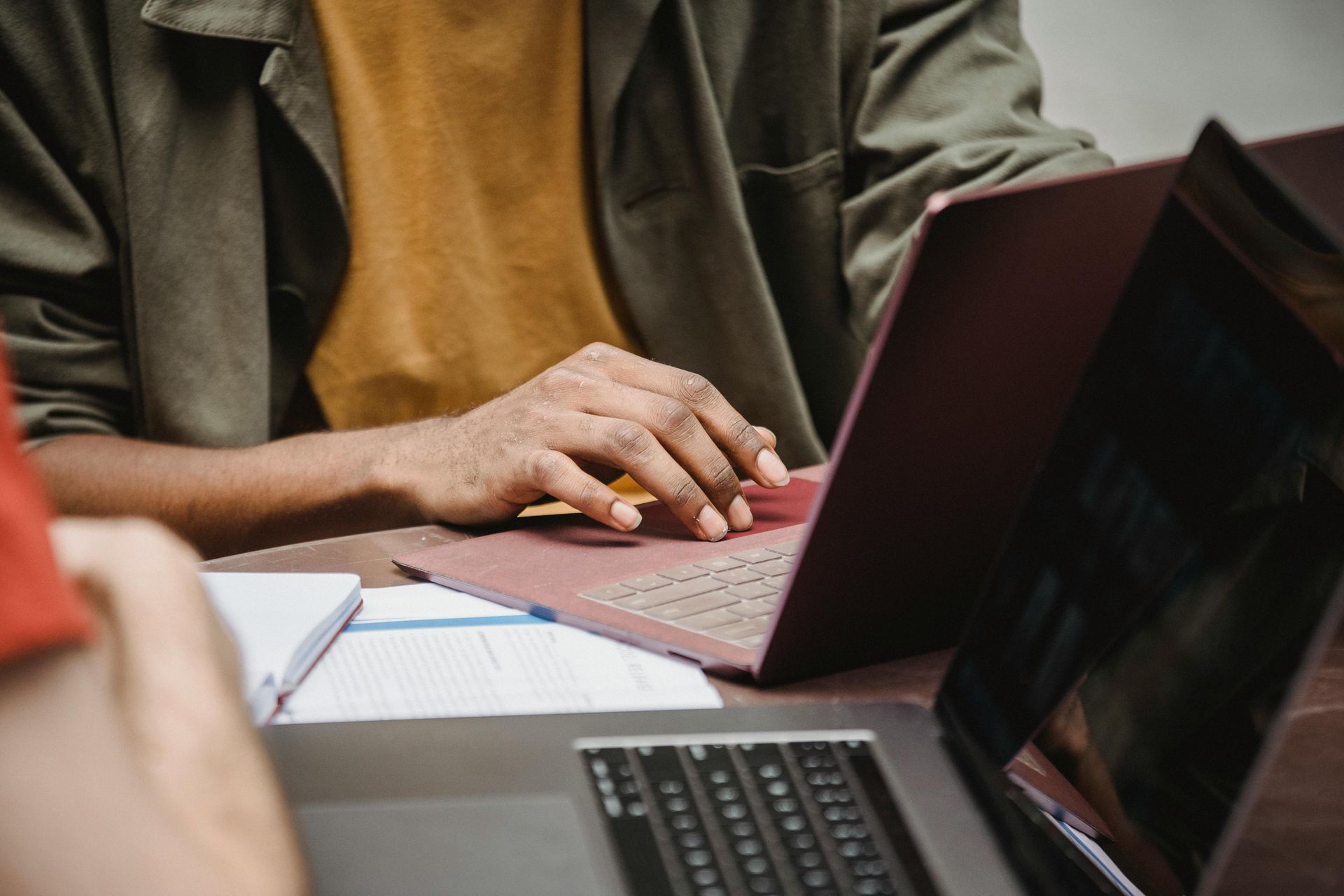 A man is typing on a laptop computer while sitting at a table.