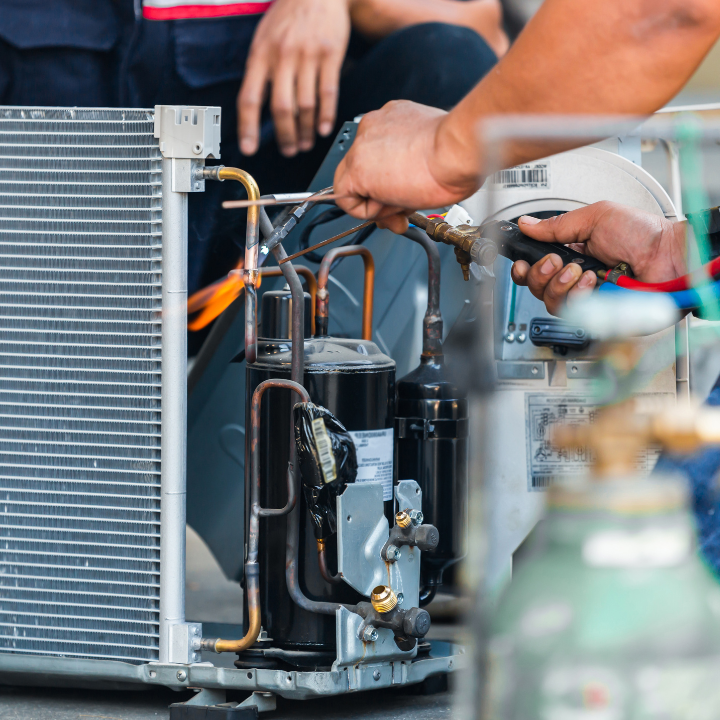 A man is working on an air conditioner with a wrench.