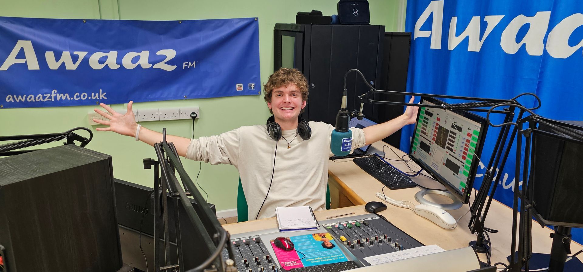 A man wearing headphones is sitting at a desk in front of a computer.