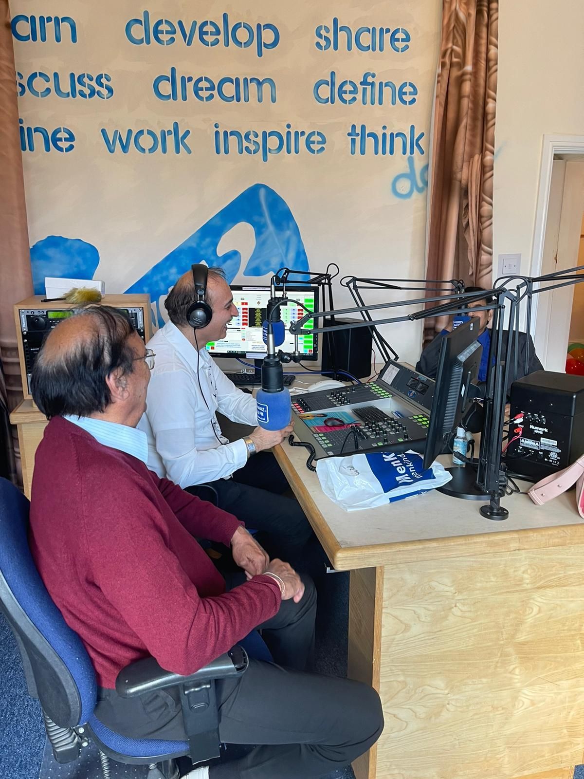 Two men are sitting at a desk in front of a microphone.