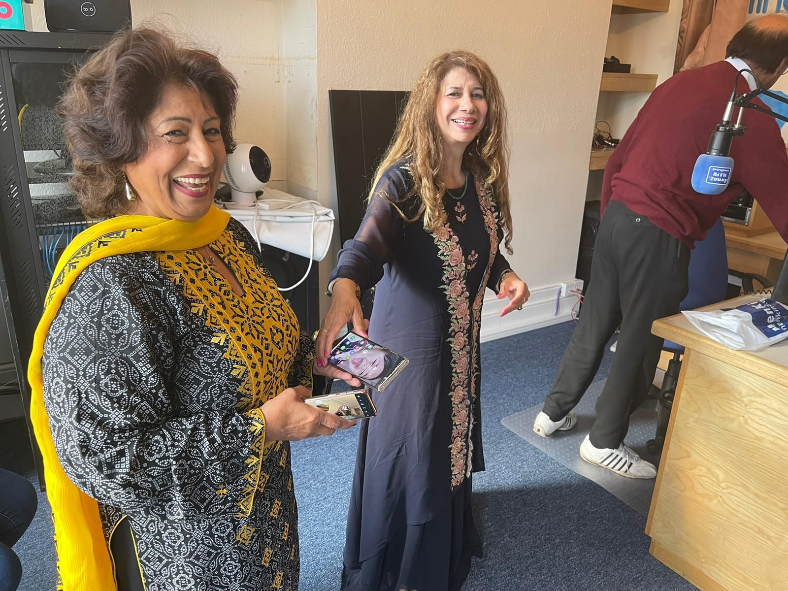 Two women are standing next to each other in a room and smiling