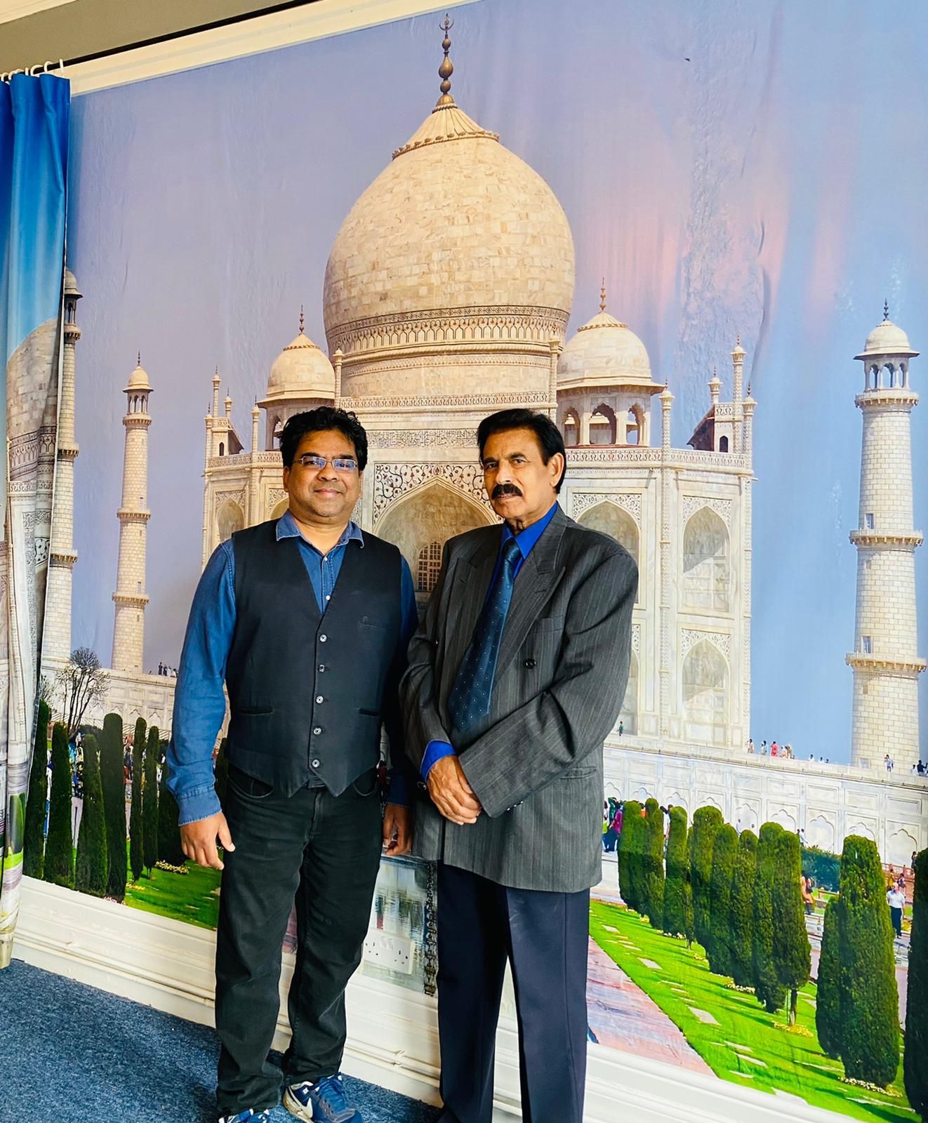 Two men standing in front of a taj mahal mural