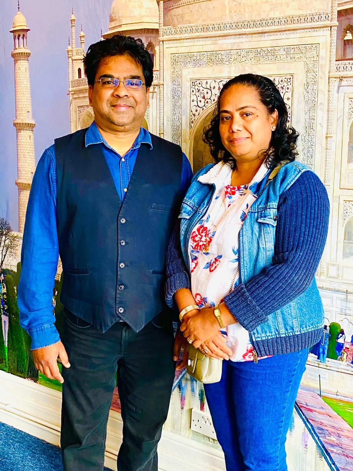A man and a woman are posing for a picture in front of a taj mahal.