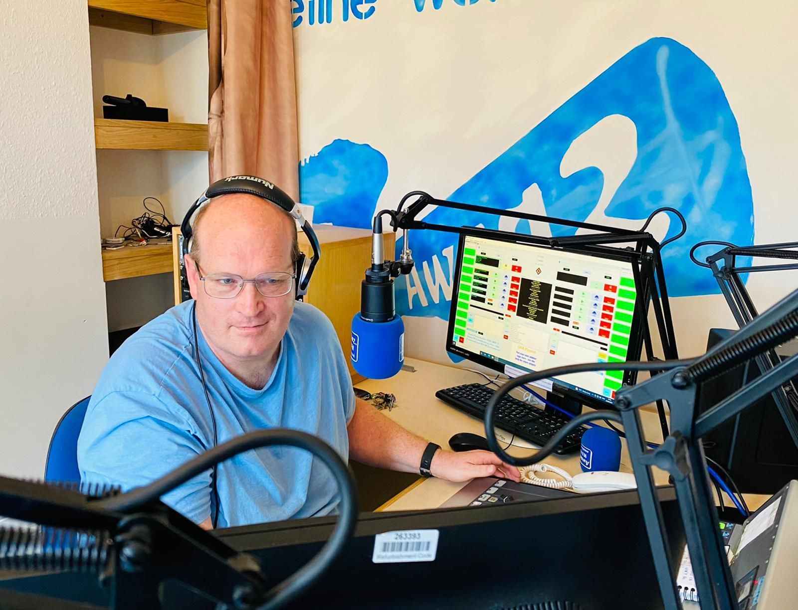 A man wearing headphones is sitting at a desk in front of a computer.