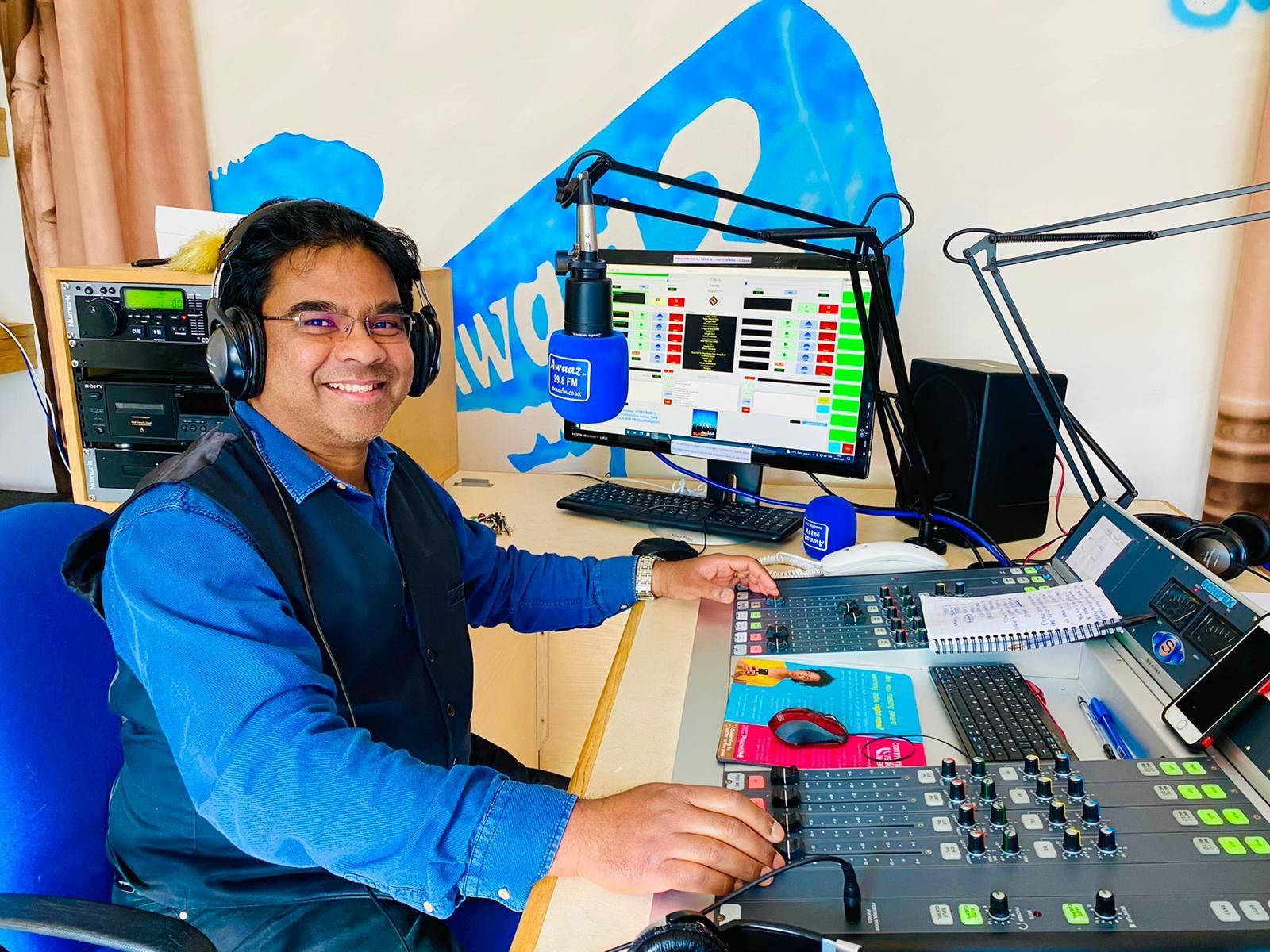 A man wearing headphones is sitting at a desk in front of a computer.