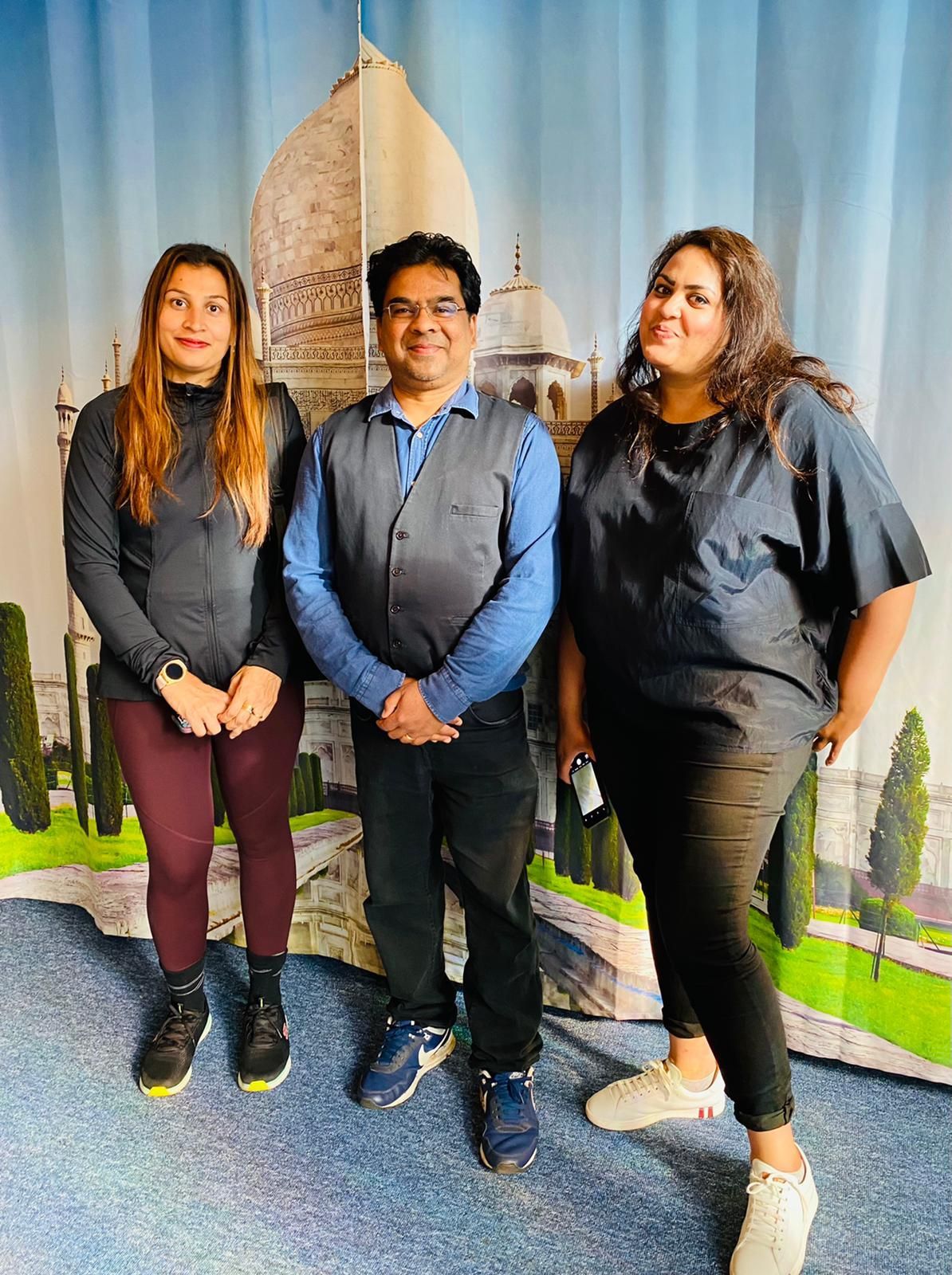 A man and two women are posing for a picture in front of a curtain.