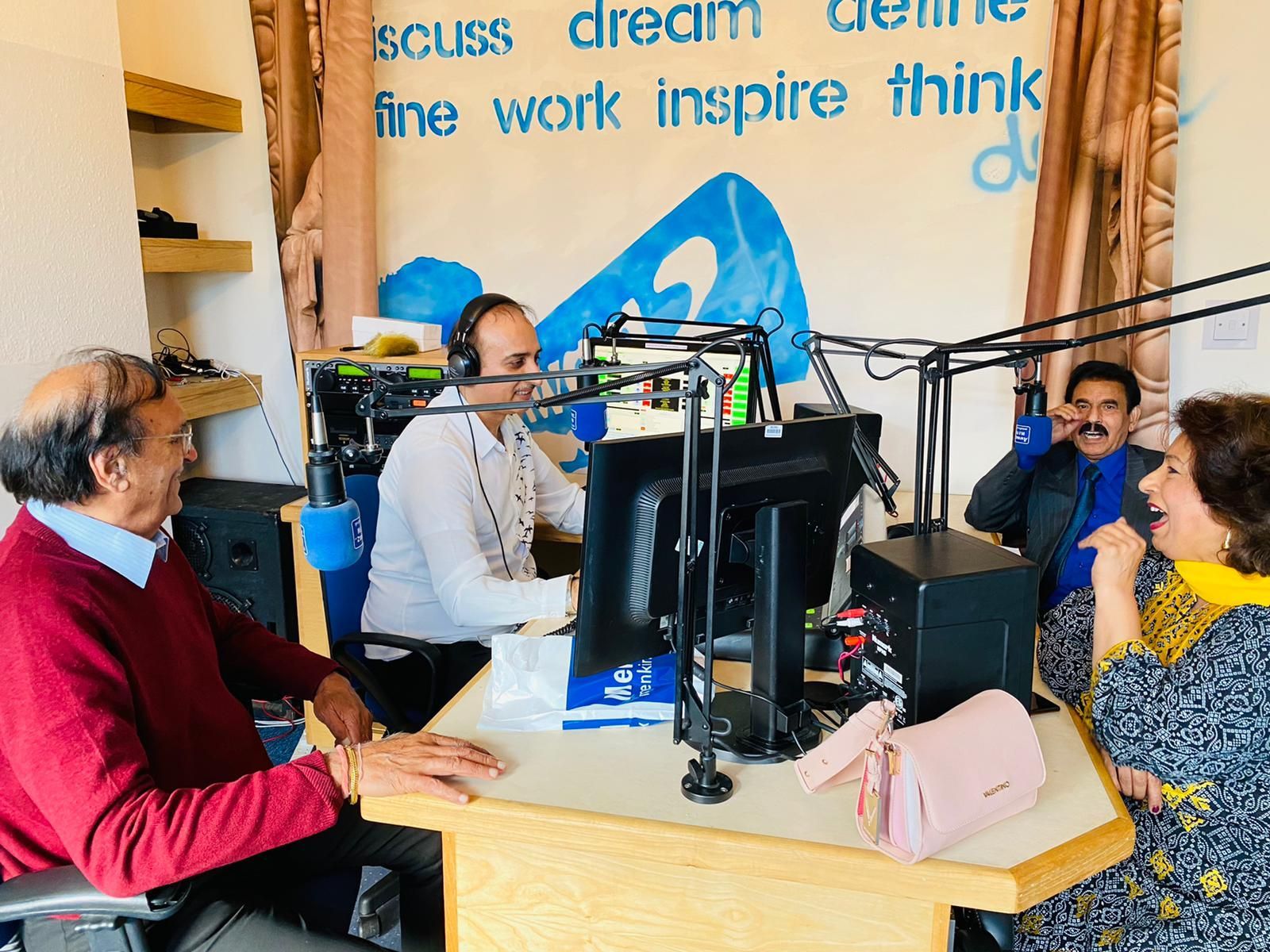 A group of people are sitting at a table in front of a microphone