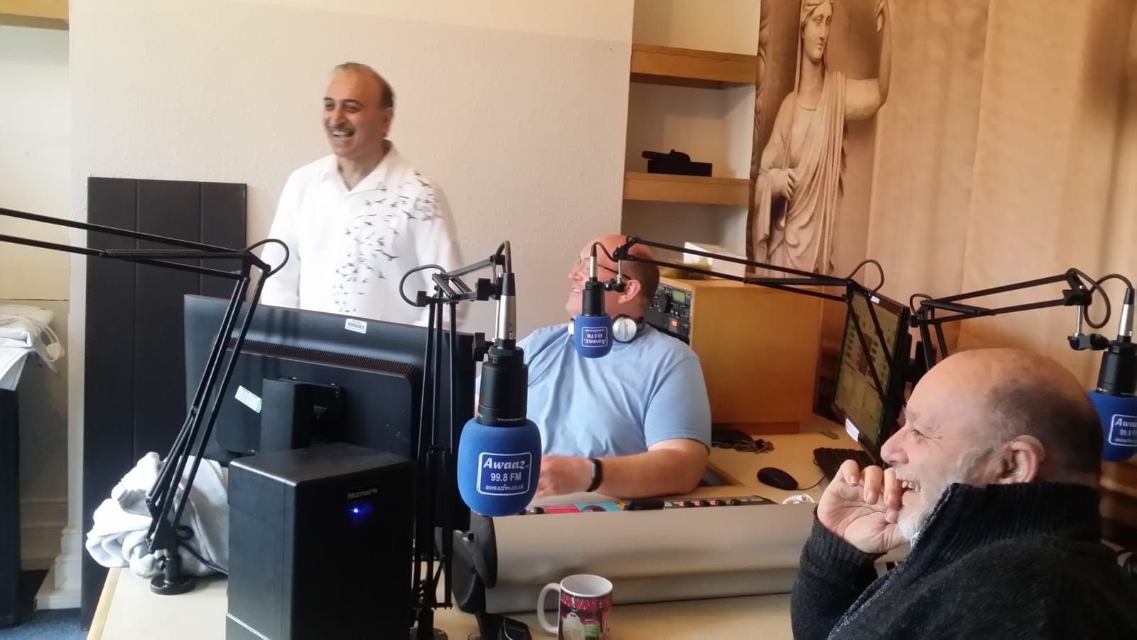 A group of men are sitting in front of microphones in a studio.