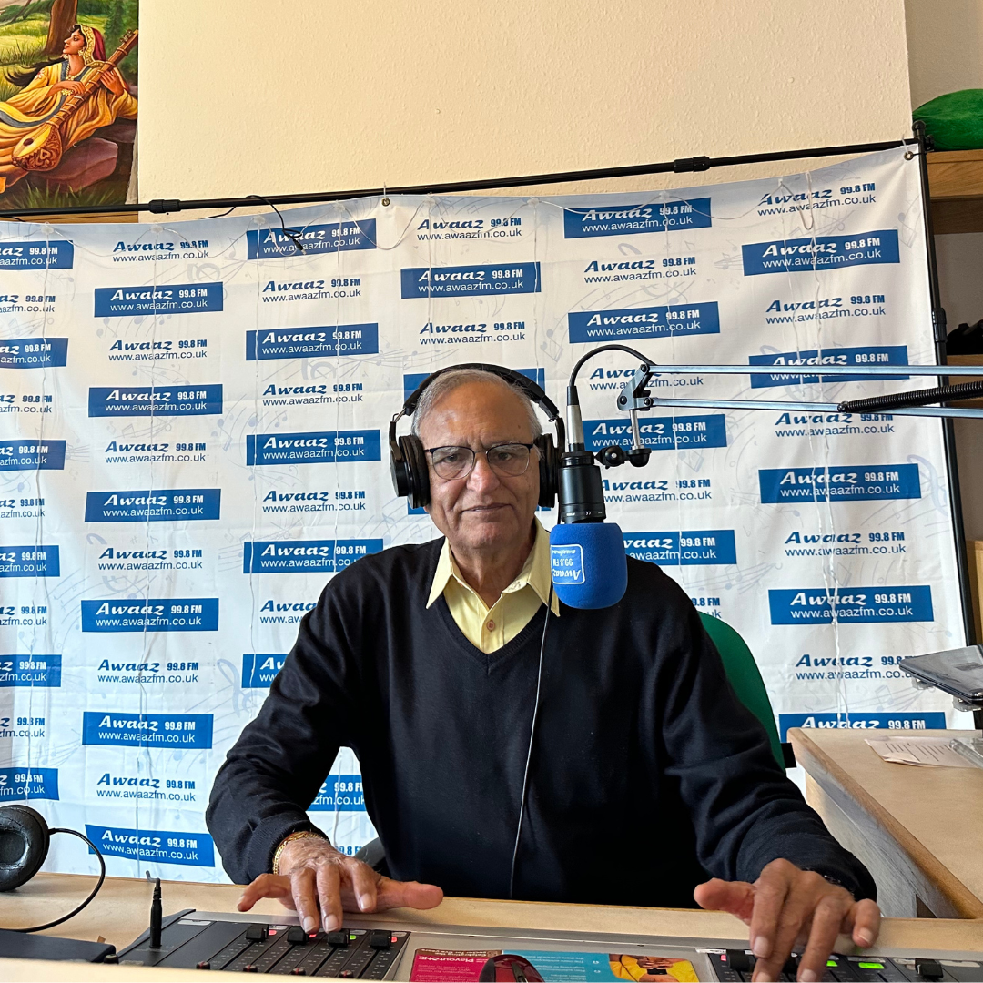 A man wearing headphones is sitting at a desk in front of a microphone