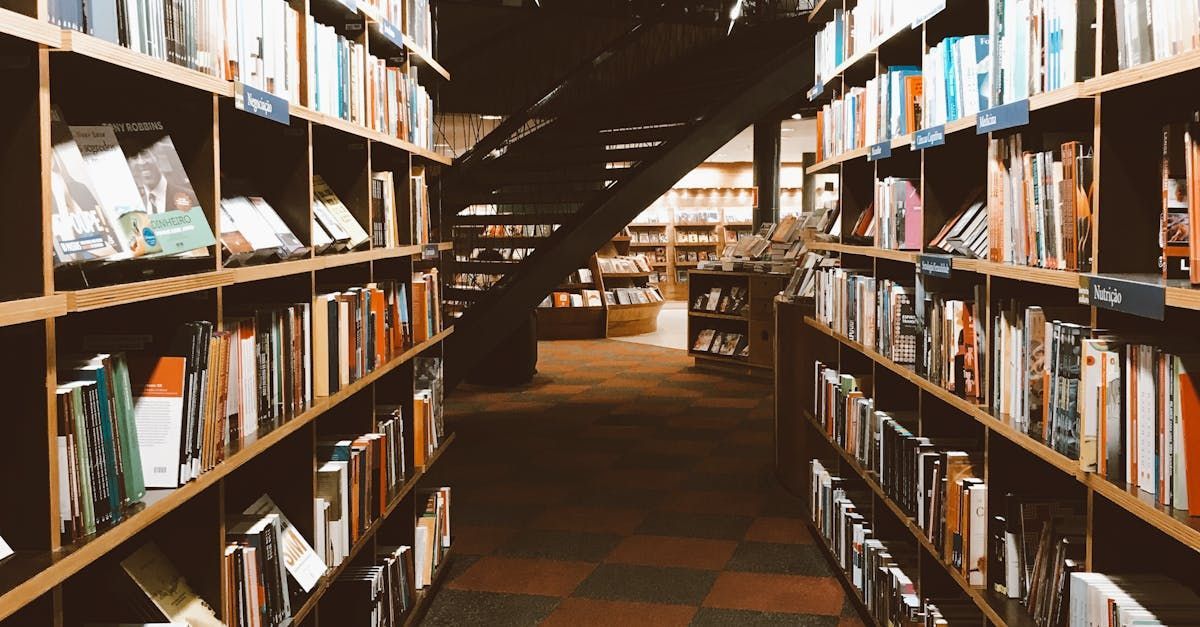 A library filled with lots of books on shelves and a staircase.