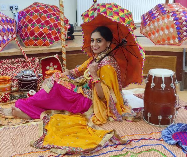 A woman is sitting on the floor holding an umbrella.