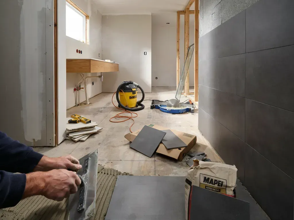 Bathroom under renovation with tools, tiles, and construction debris on the floor