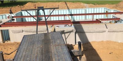 Construction site with a partially built concrete structure. Steel beams cross the top.