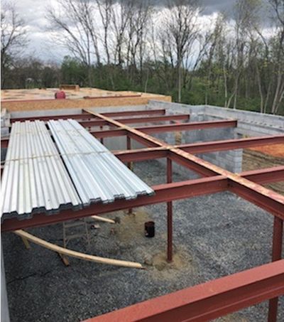 Construction site with exposed steel beams, concrete blocks, and corrugated metal sheets.