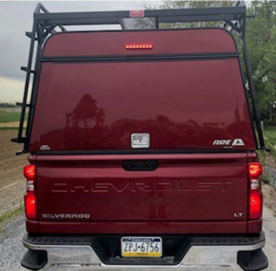 Red Chevrolet Silverado truck with matching topper and ladder rack, license plate ZPJ-6756.