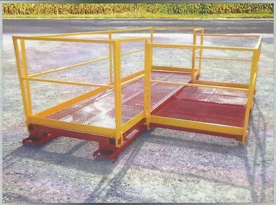 Yellow and red metal work platform with railings on a gravel surface.