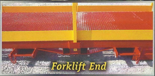 Forklift end of a yellow and red industrial trailer with a diamond mesh surface.
