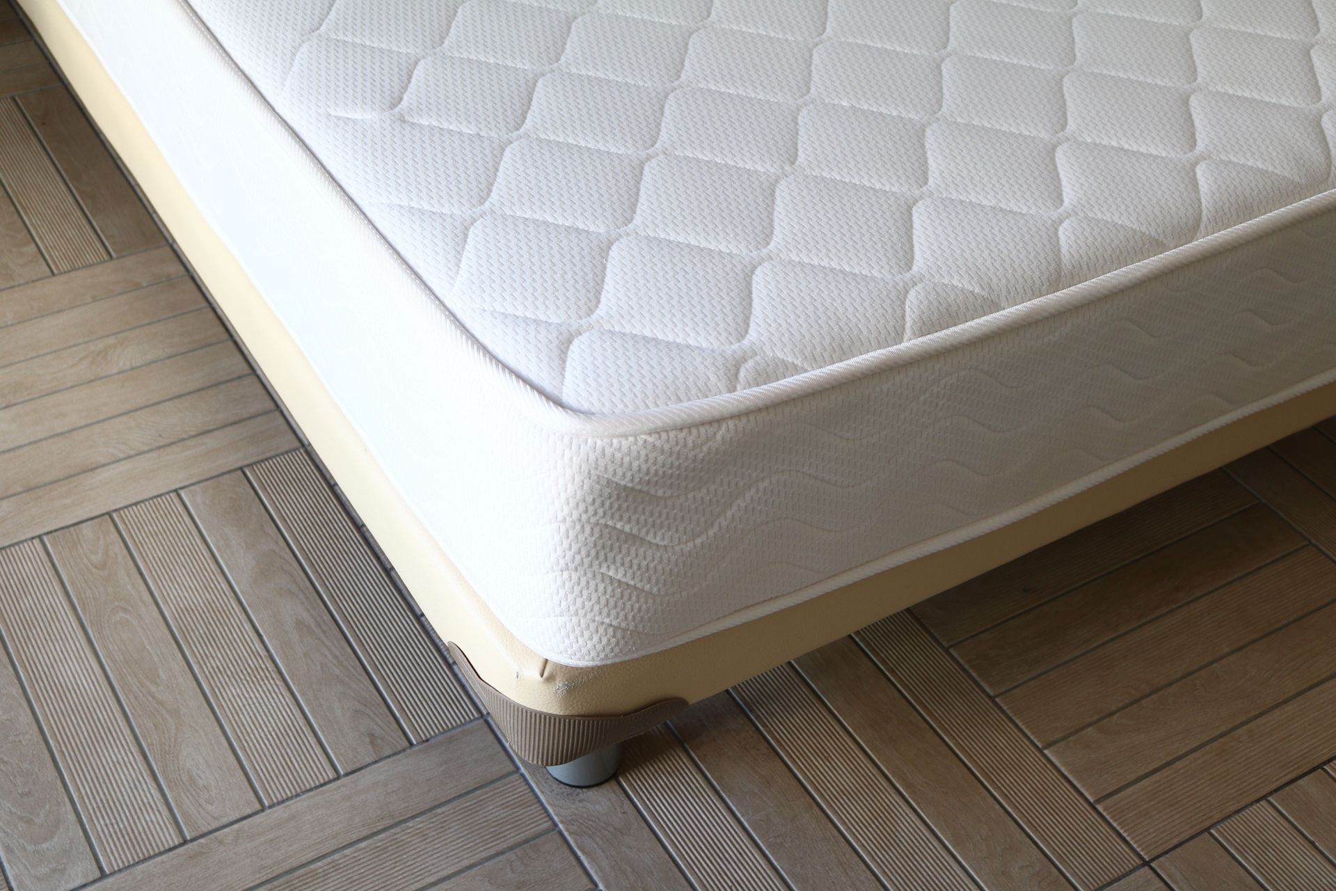 A white mattress is sitting on a wooden floor.