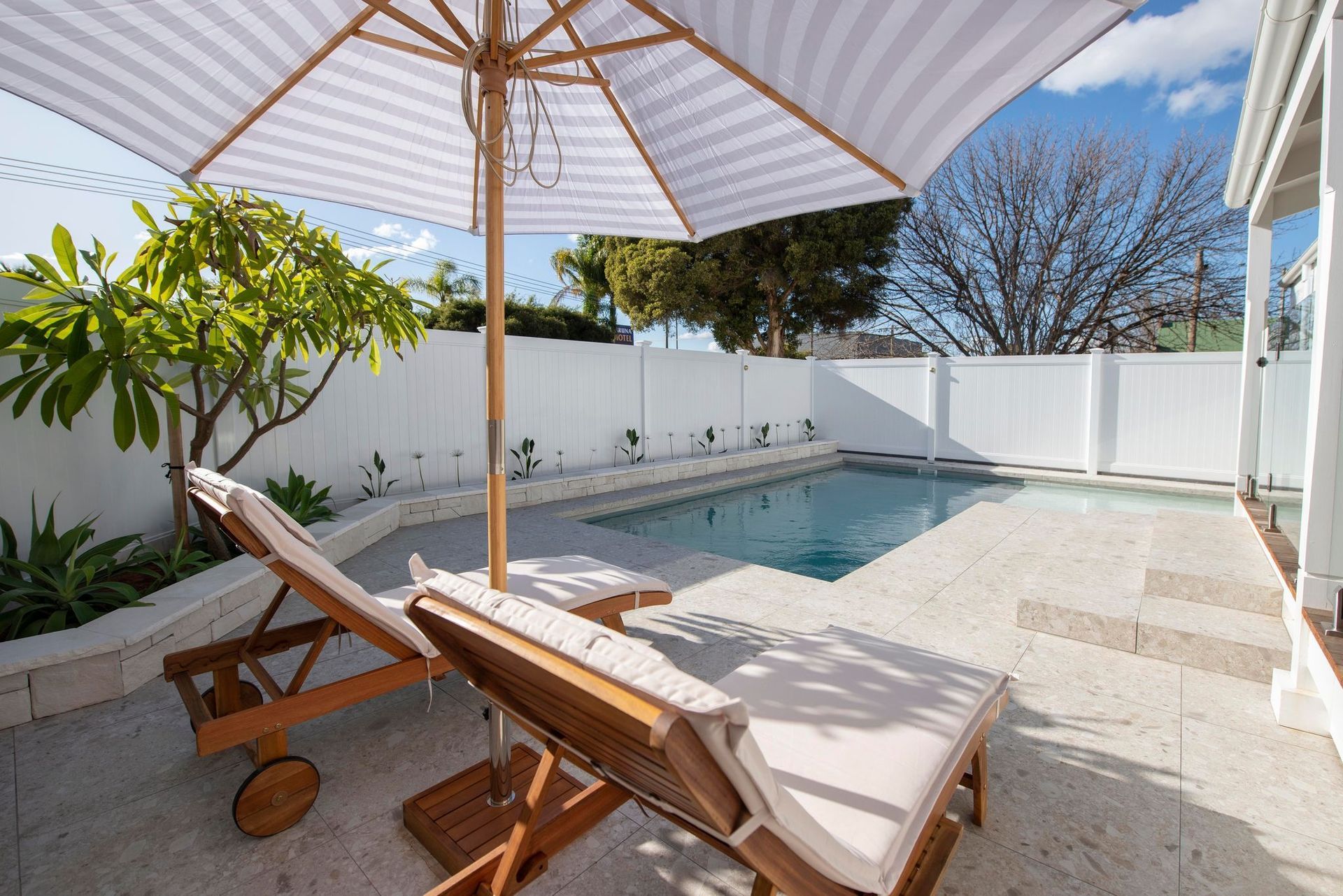 Two Lounge Chairs Under a Striped Umbrella — Swan Hill Pool & Spa Centre in Swan Hill, VIC