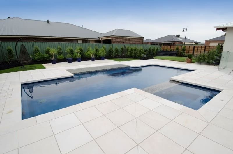 A Blue-Tiled Swimming Pool Surrounded by White Paving Stones — Swan Hill Pool & Spa Centre in Swan Hill, VIC