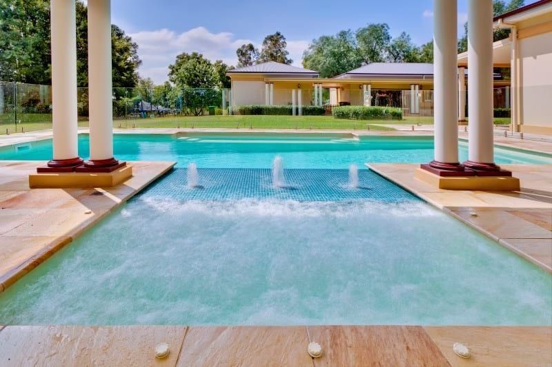 Pool with Fountains, Large Pillars and A View of A House — Swan Hill Pool & Spa Centre in Swan Hill, VIC