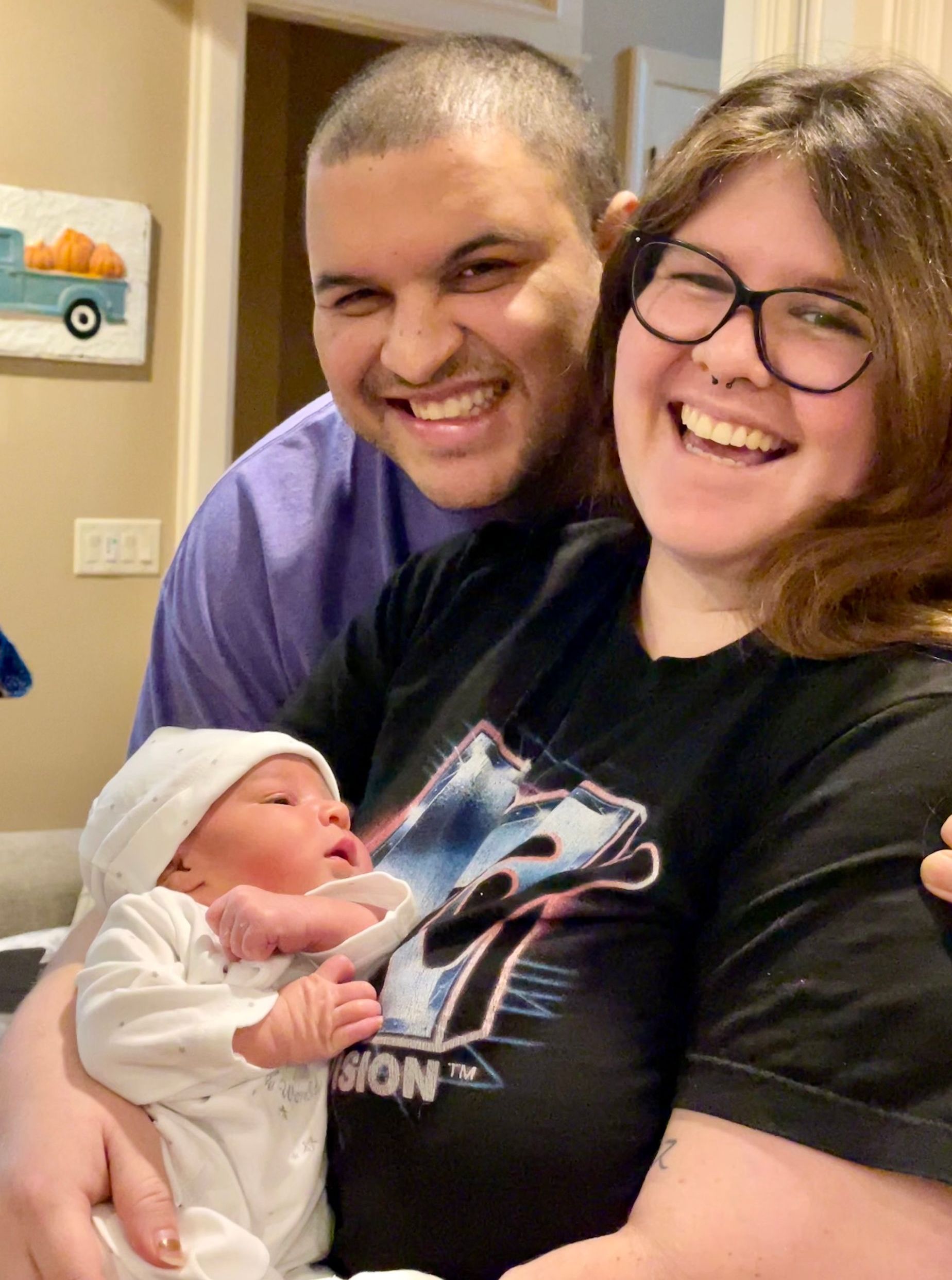Smiling client family holding their baby during a postpartum visit.