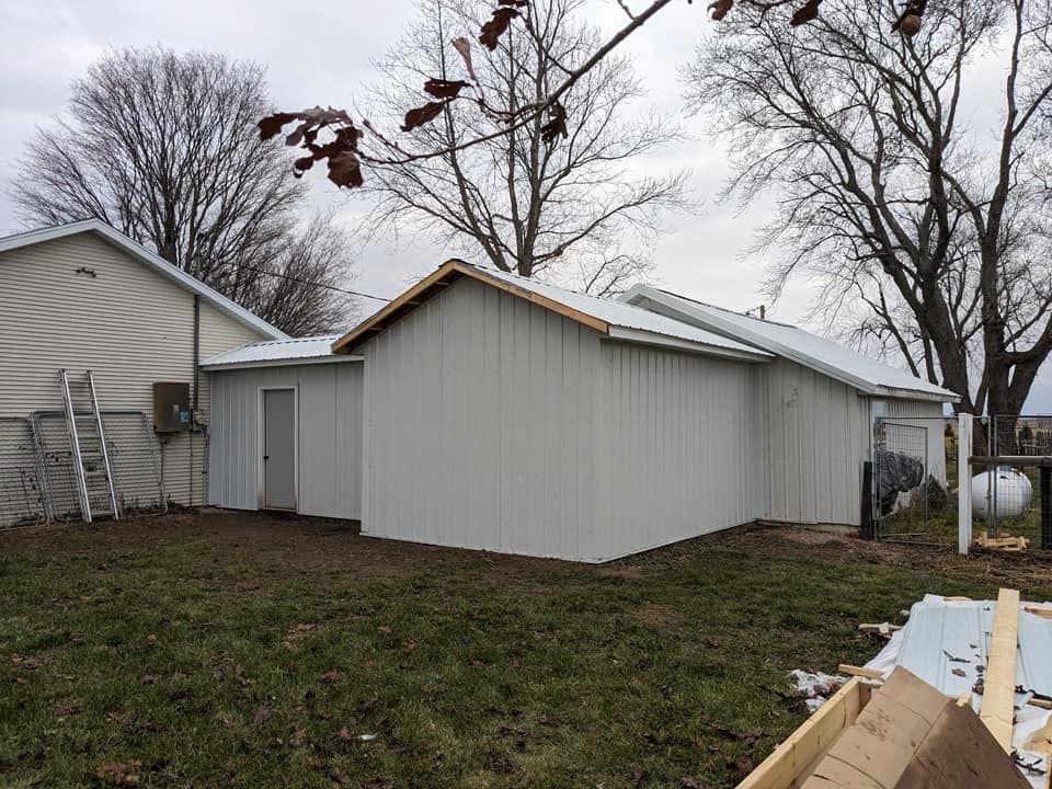 A light-colored metal addition attached to the side of a house, set in a grassy yard on an overcast day.