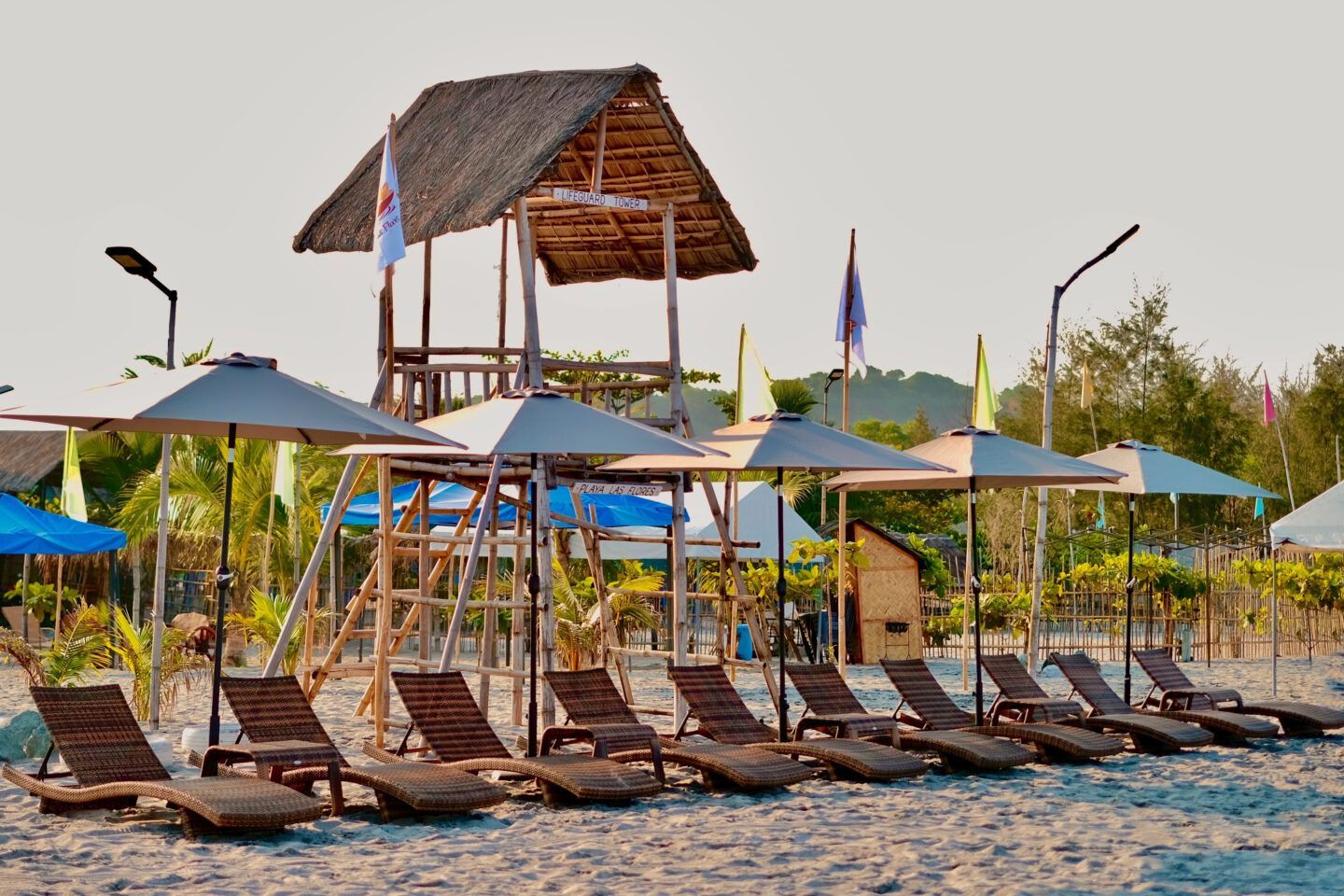 A beach with chairs and umbrellas and a lifeguard tower
