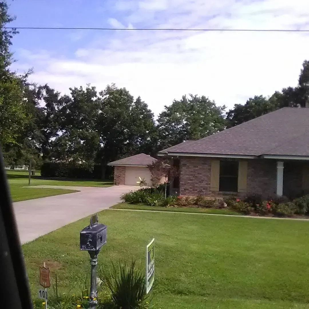 House with attached garage, brick exterior, green lawn, blue sky, mailbox in the foreground.