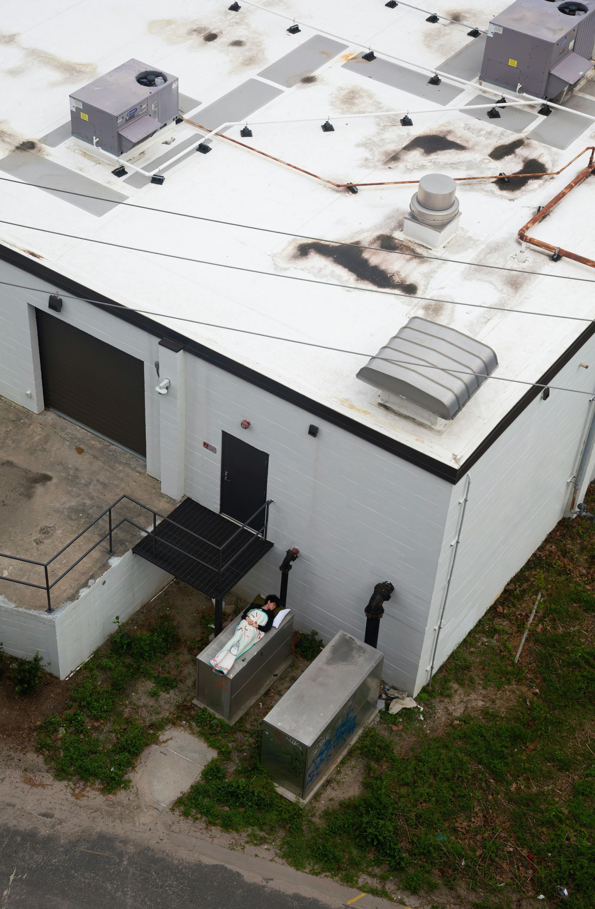 White building with a black door, several vents, and solar panels outside.