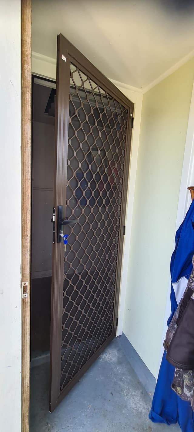 A person is standing in front of a door with a chain link fence.