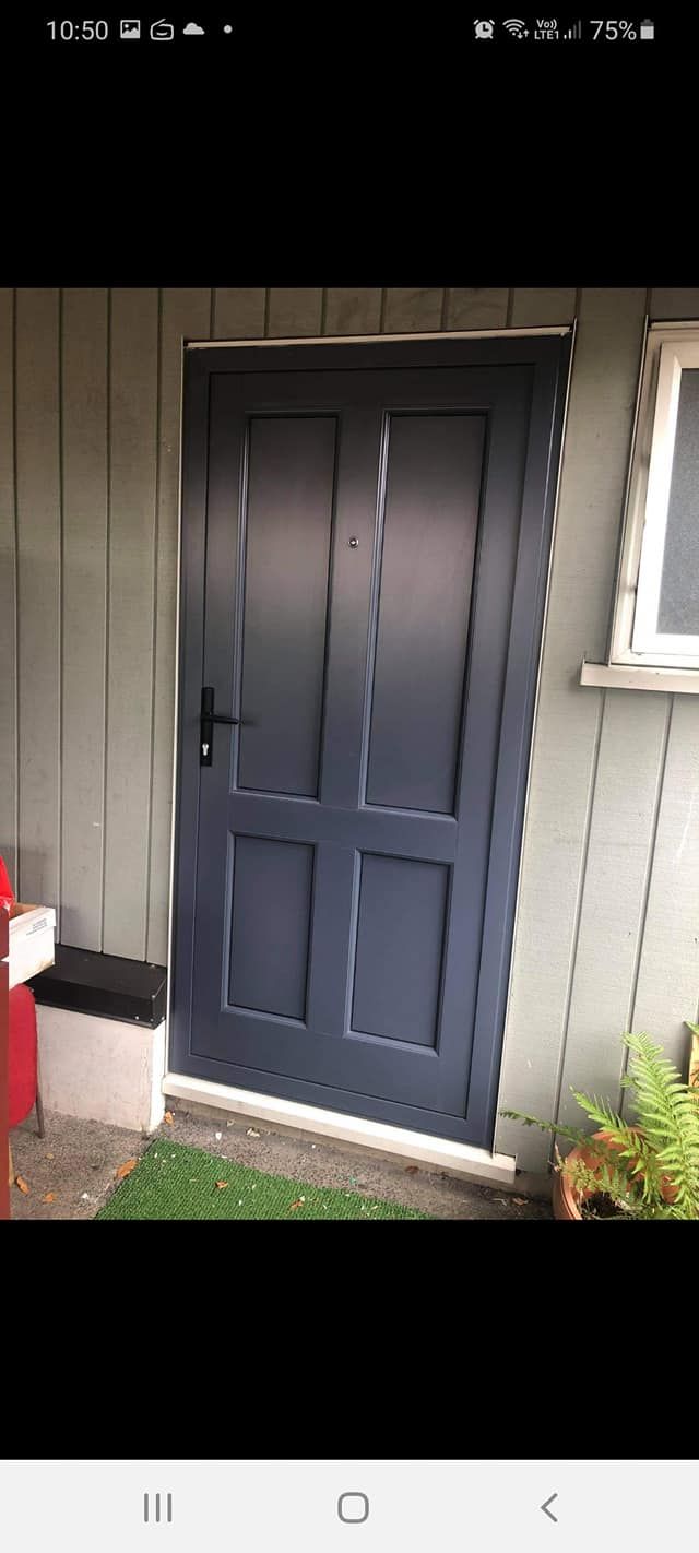 A blue door is sitting on the side of a building next to a window.