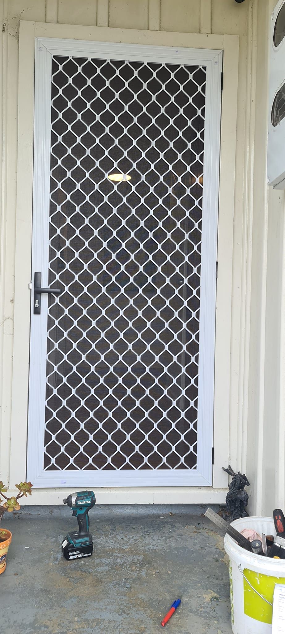 A white door with a black screen and a drill in front of it.