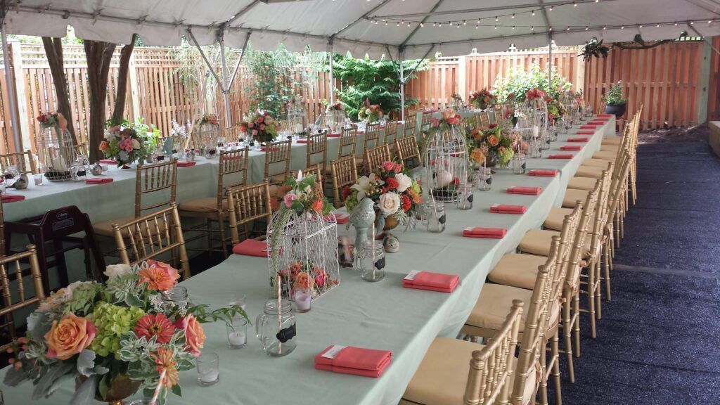 A Long Table With Flowers on It Under a Tent