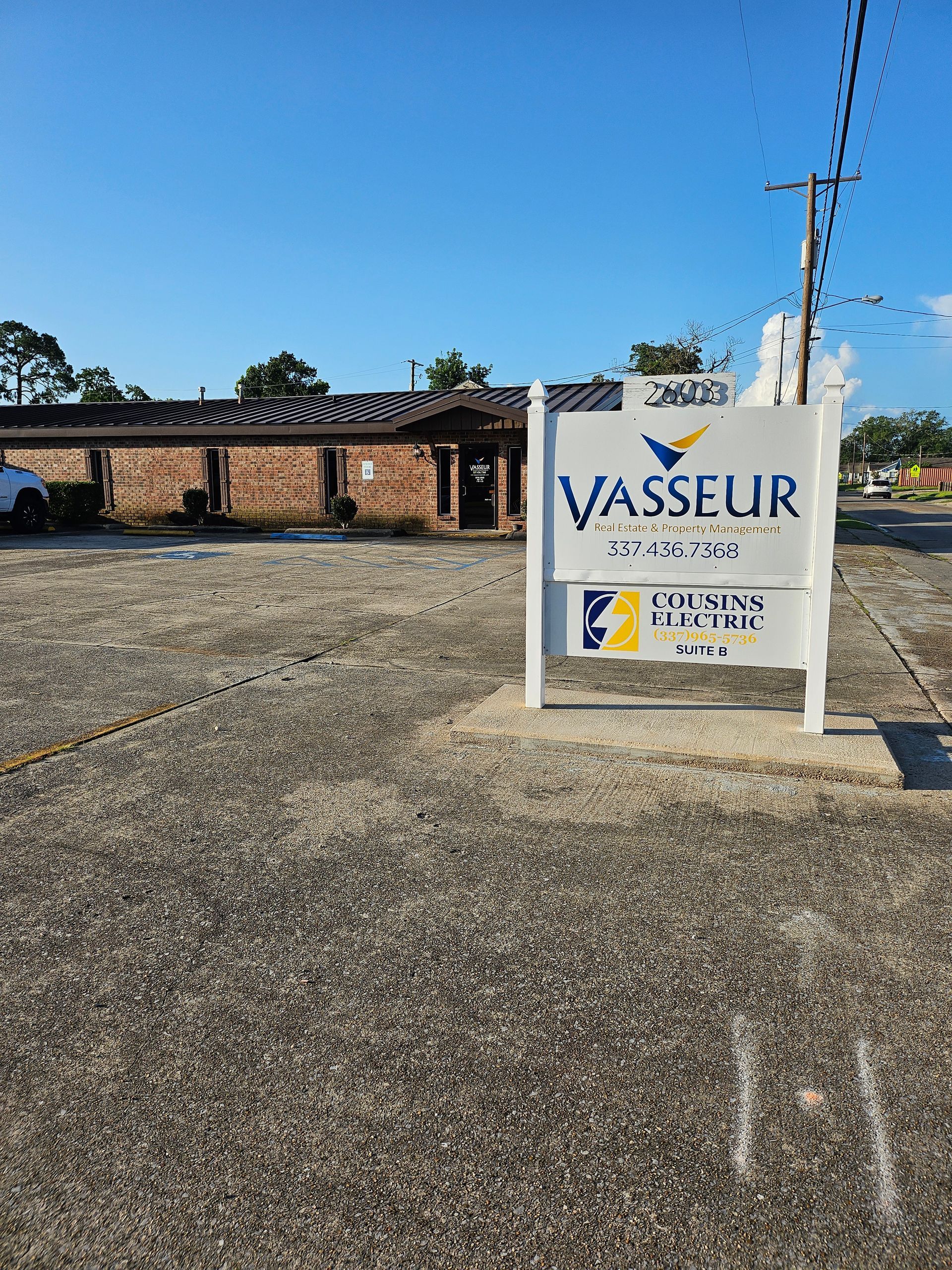 A white sign is sitting in a parking lot in front of a building.