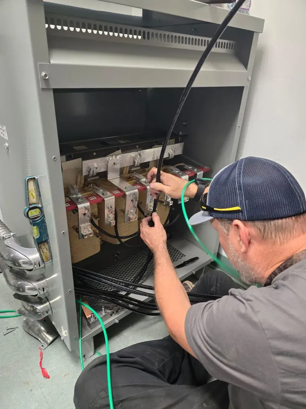 A man is sitting on the floor working on a electrical box.