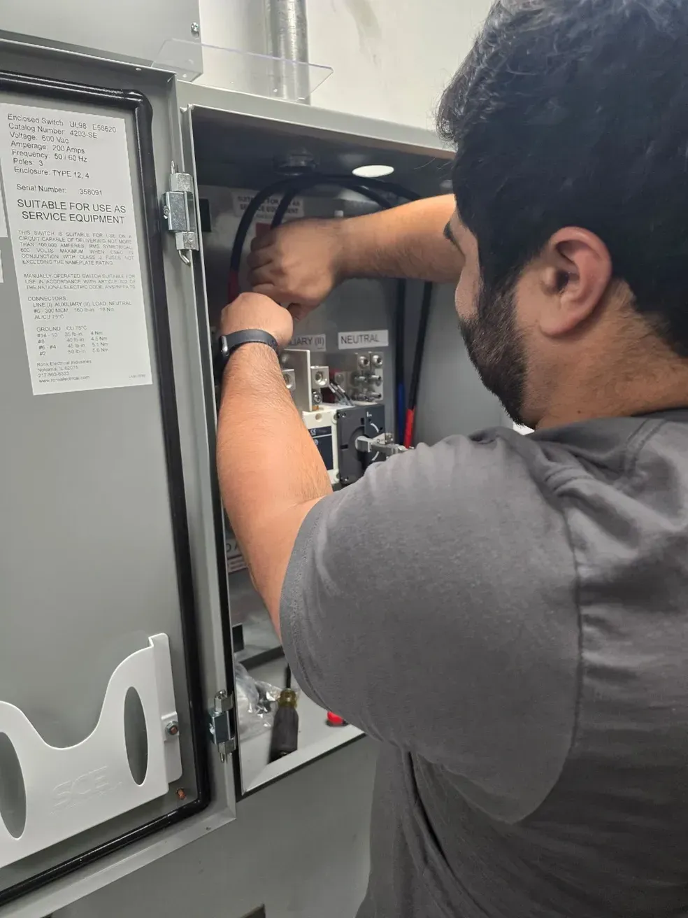 A man is working on an electrical box in a room.