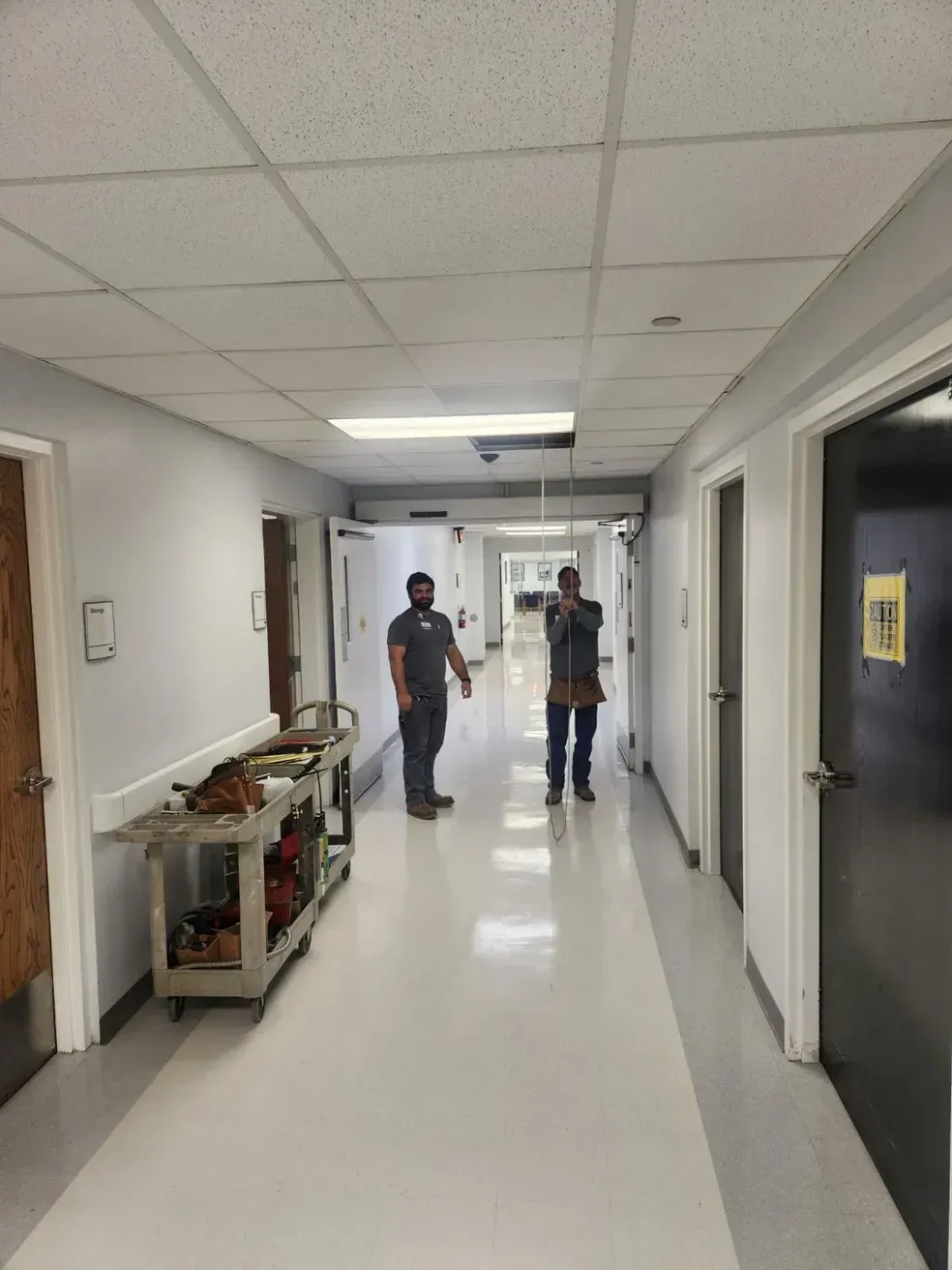 Two men are walking down a hospital hallway.