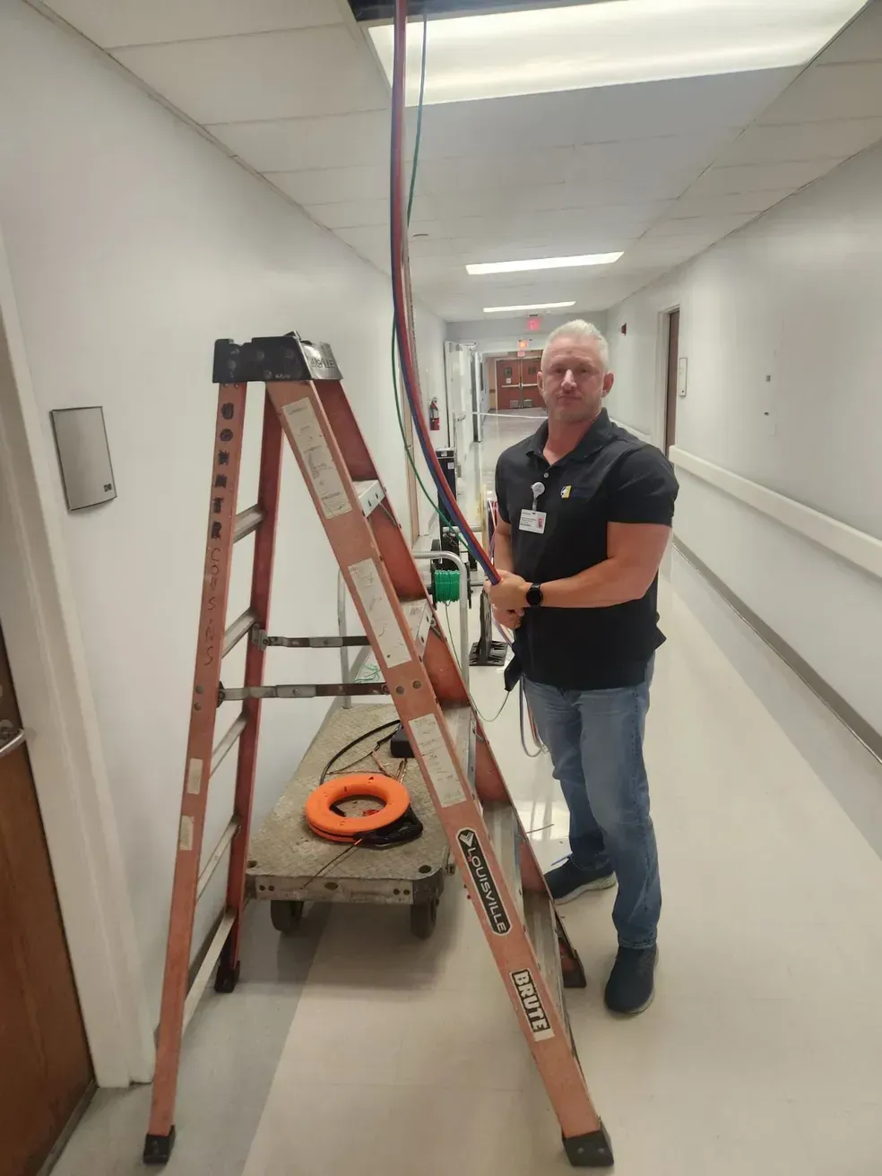 A man standing next to a ladder in a hallway