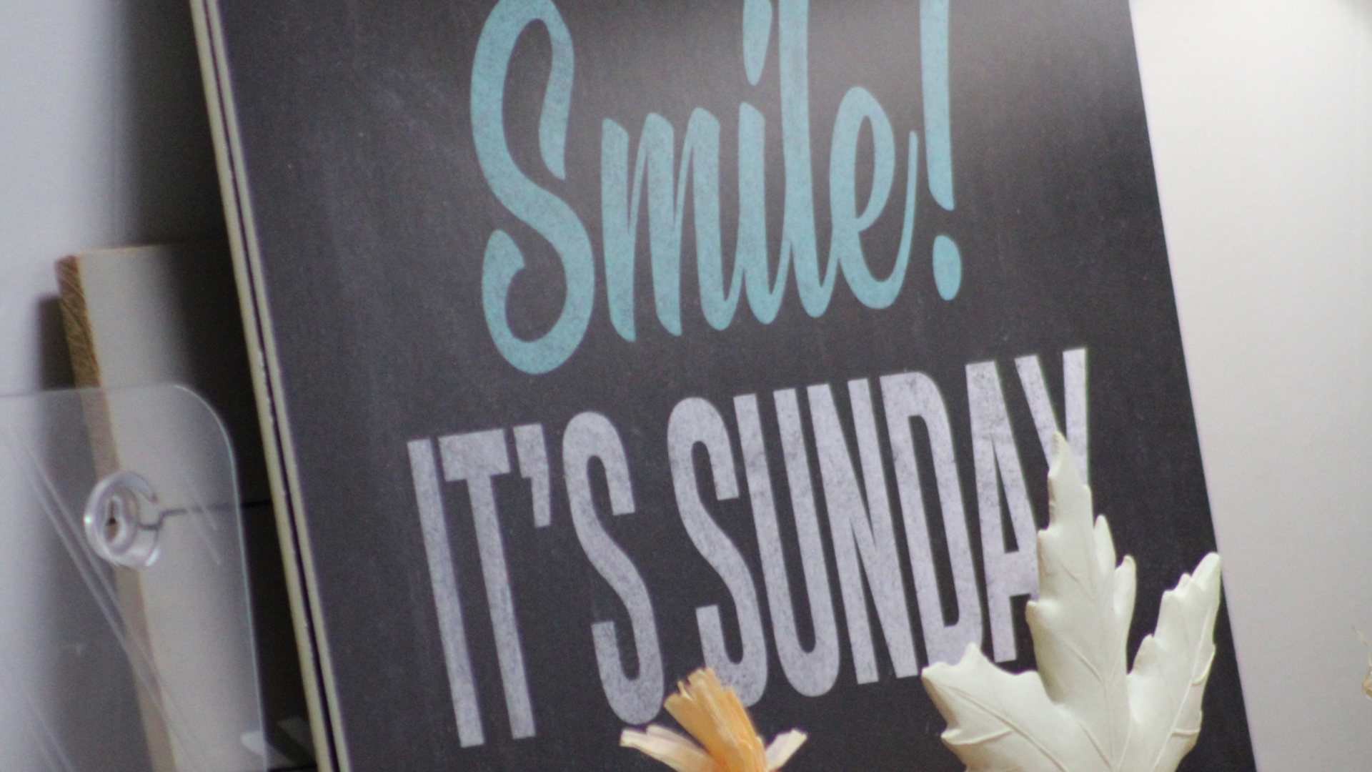 A sign that says smile it 's sunday is hanging on a wall.
