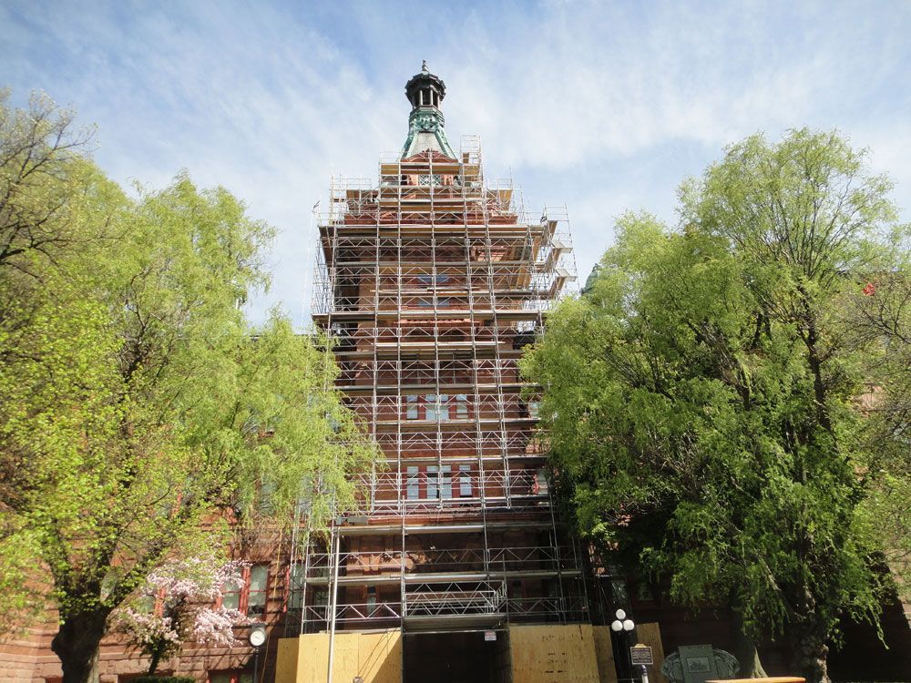 A large building with scaffolding around it and trees in front of it