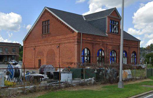 A large red brick building with a roof and a lot of windows.