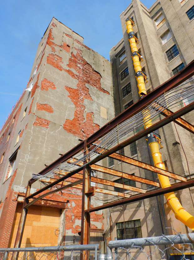A building under construction with a yellow pipe coming out of it.