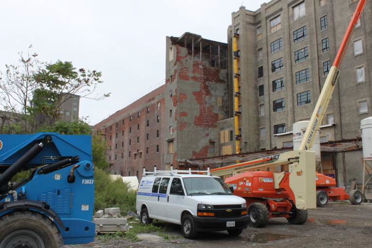 A white van is parked in front of a large building.