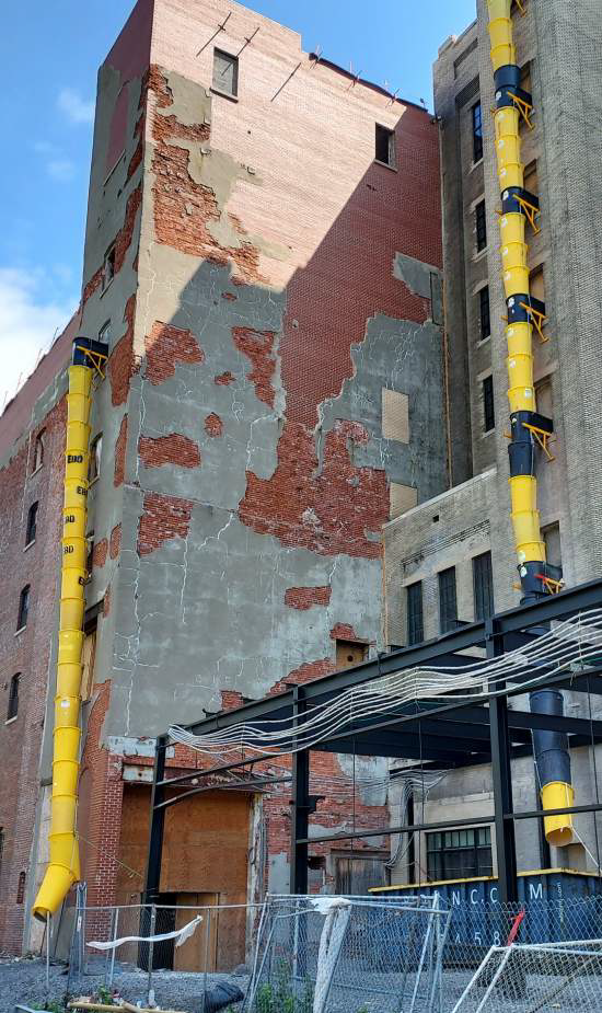 A brick building with yellow pipes attached to it.