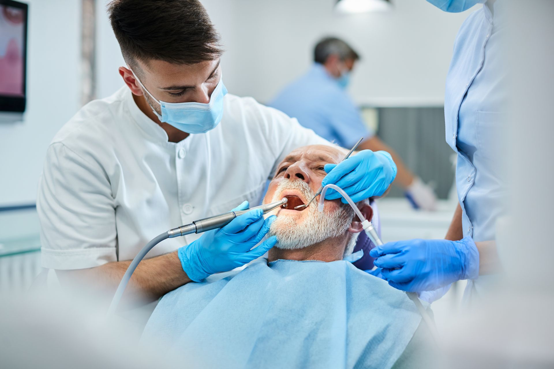 Dentist and assistant performing a dental procedure on a patient in a clinic.
