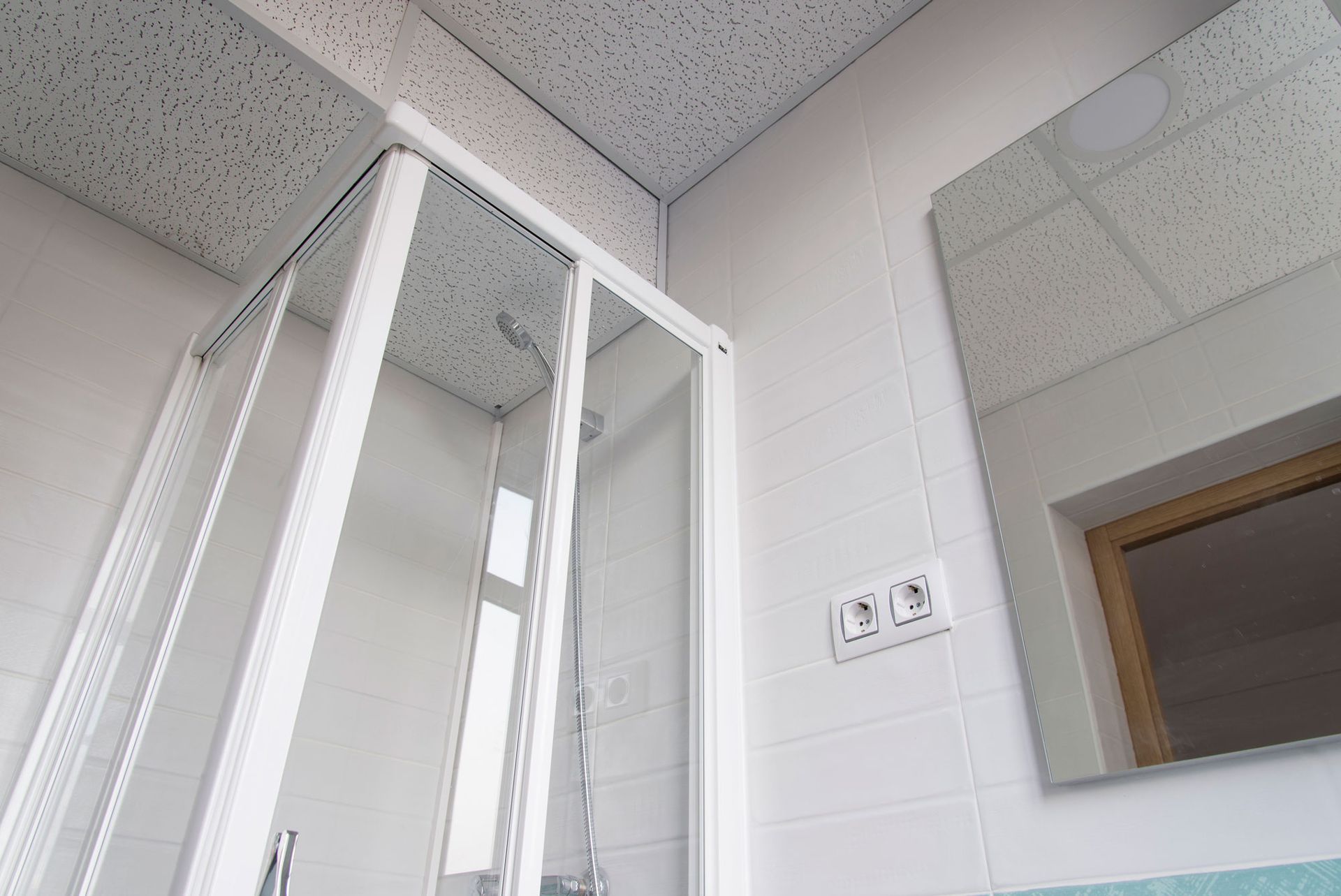 Shower door enclosure and ceiling of small modern toilet with white tiles, minimalist bathroom desig