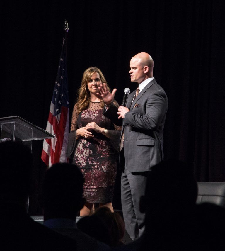 Tye speaking onstage with Ann