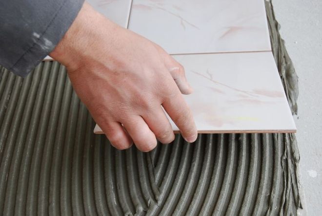 a person is laying a tile on the floor