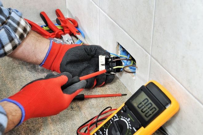 a man is working on an electrical outlet with a multimeter